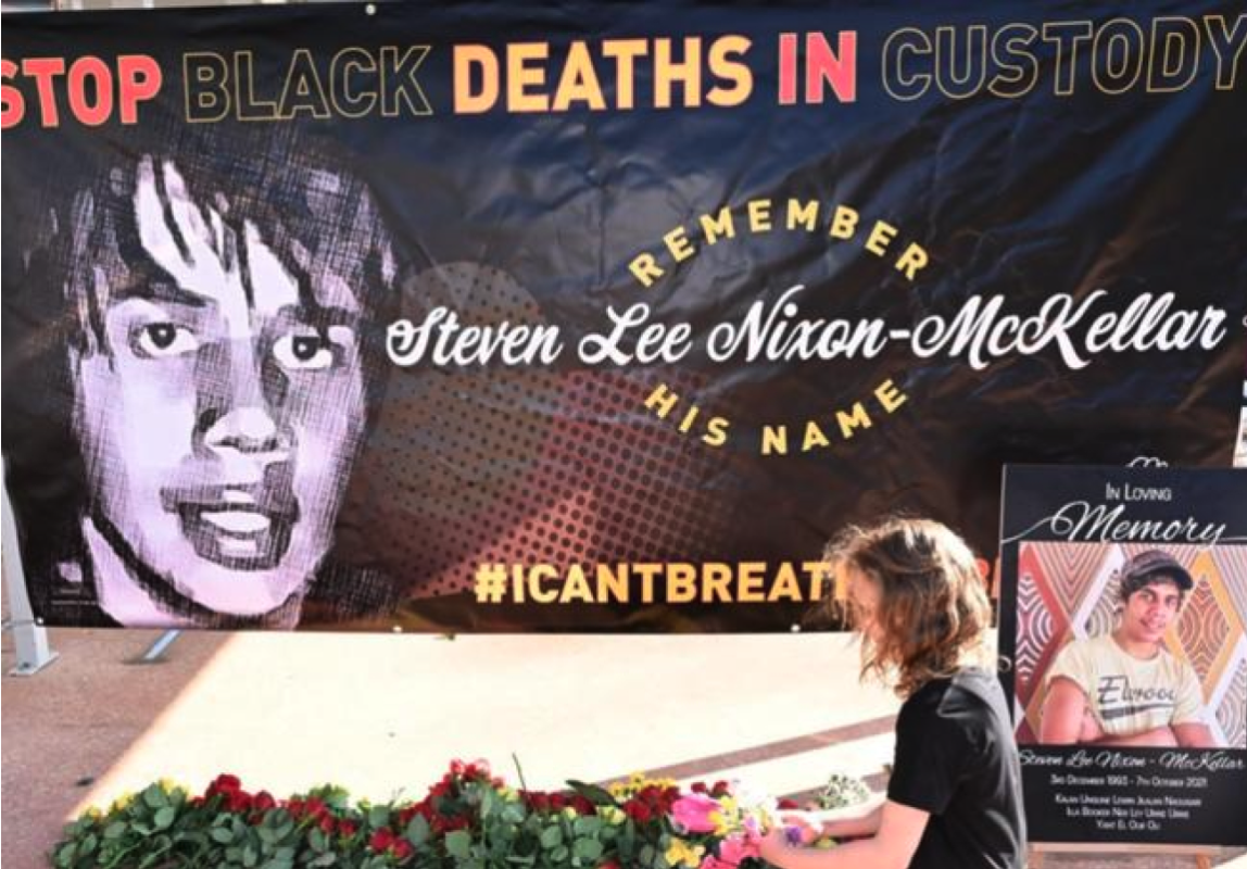 A banner featuring Steven's face and call to "Stop Black deaths in custody" was raised in a rally. (Image: Darren England/AAP PHOTOS)