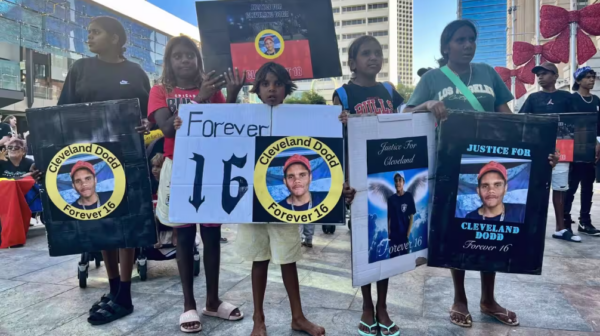 People hold placards during a rally calling for justice following the death of Indigenous teen Cleveland Dodd, who self-harmed while being detained in and adult prison, in Perth. Source: AAP / Aaron Bunch/AAP Image